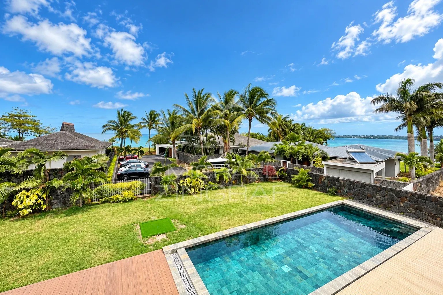 Villa avec vue mer à Vieux Grand Port Vue d'une villa avec piscine et jardin, entourée de palmiers et d'autres résidences, à Vieux Grand Port.