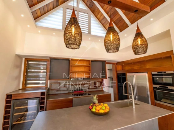 Cuisine moderne d'une villa contemporaine avec îlot central et éclairage suspendu.