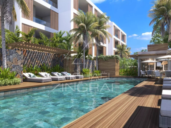 Swimming pool surrounded by sun loungers and palm trees in a residential complex in Grand Baie.