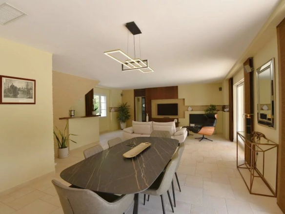 Open-concept living and dining room with a long dark marble dining table, gray chairs, and a geometric pendant light.