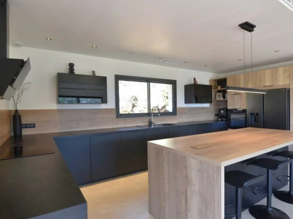Modern kitchen with dark cabinetry, a large wooden island, and a window above the sink.
