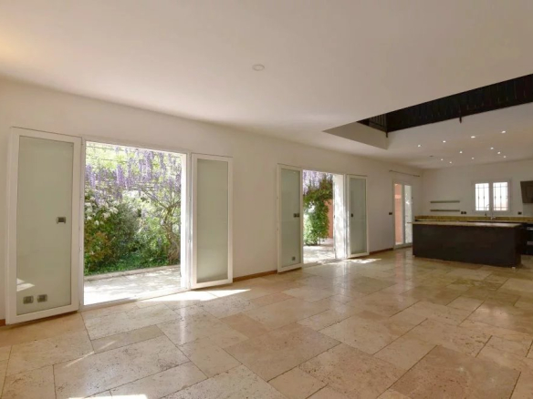 Bright open-plan living area with glass patio doors to a green garden and a dark kitchen island nearby.