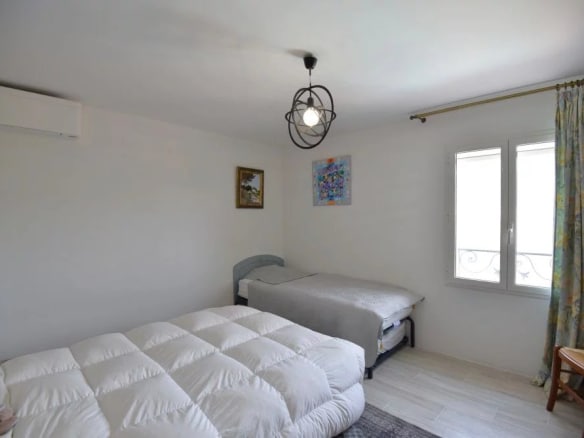 Chambre d'une villa provençale avec lit double et lit simple, décorée sobrement.