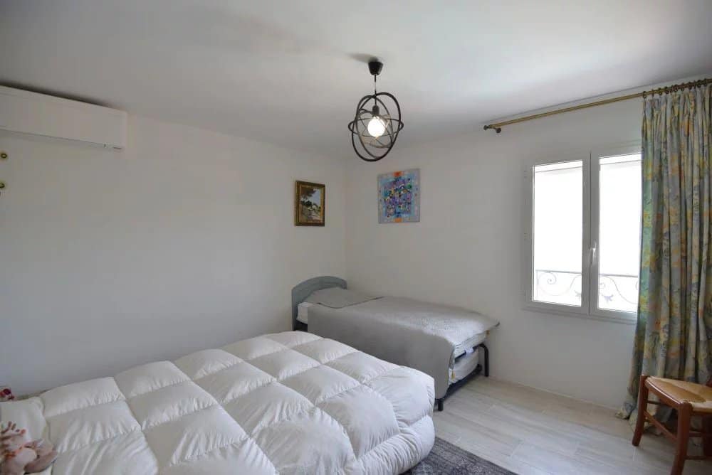 Chambre d'une villa provençale avec lit double et lit simple, décorée sobrement.