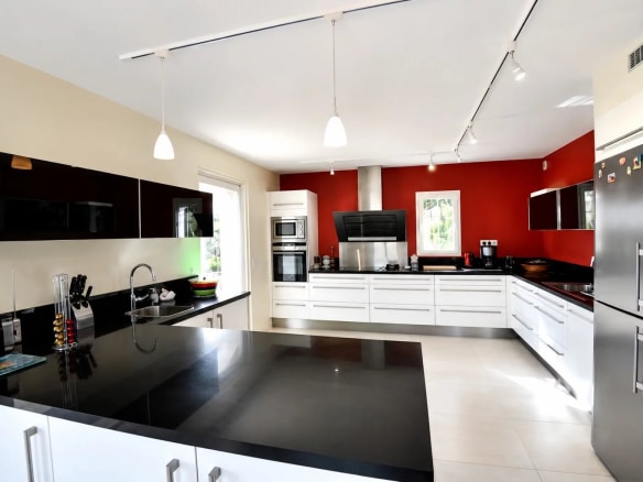 Intérieur d'une cuisine moderne avec un îlot central et des meubles noirs et blancs.