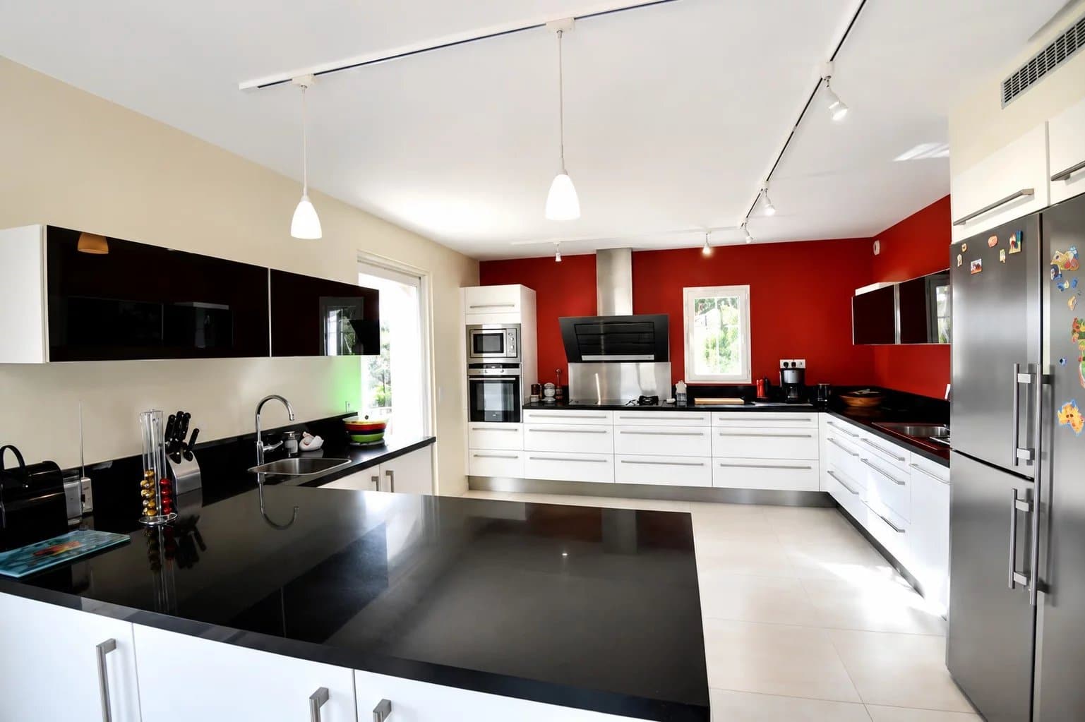 Intérieur d'une cuisine moderne avec un îlot central et des meubles noirs et blancs.