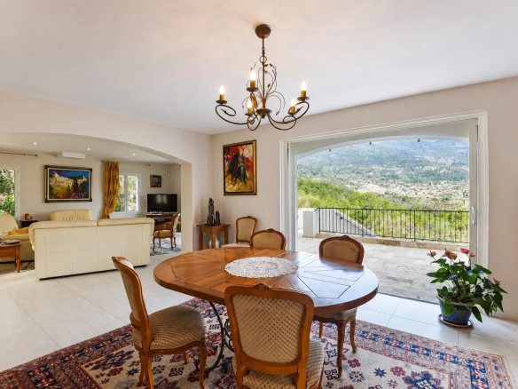 Intérieur d'une villa provençale avec une salle à manger et une vue panoramique sur la campagne.