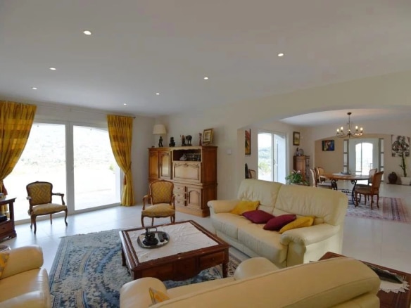 Intérieur d'une villa provençale avec salon lumineux et vue sur la campagne.