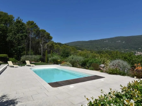 Vue de la piscine d'une villa avec un paysage verdoyant et des collines en arrière-plan.