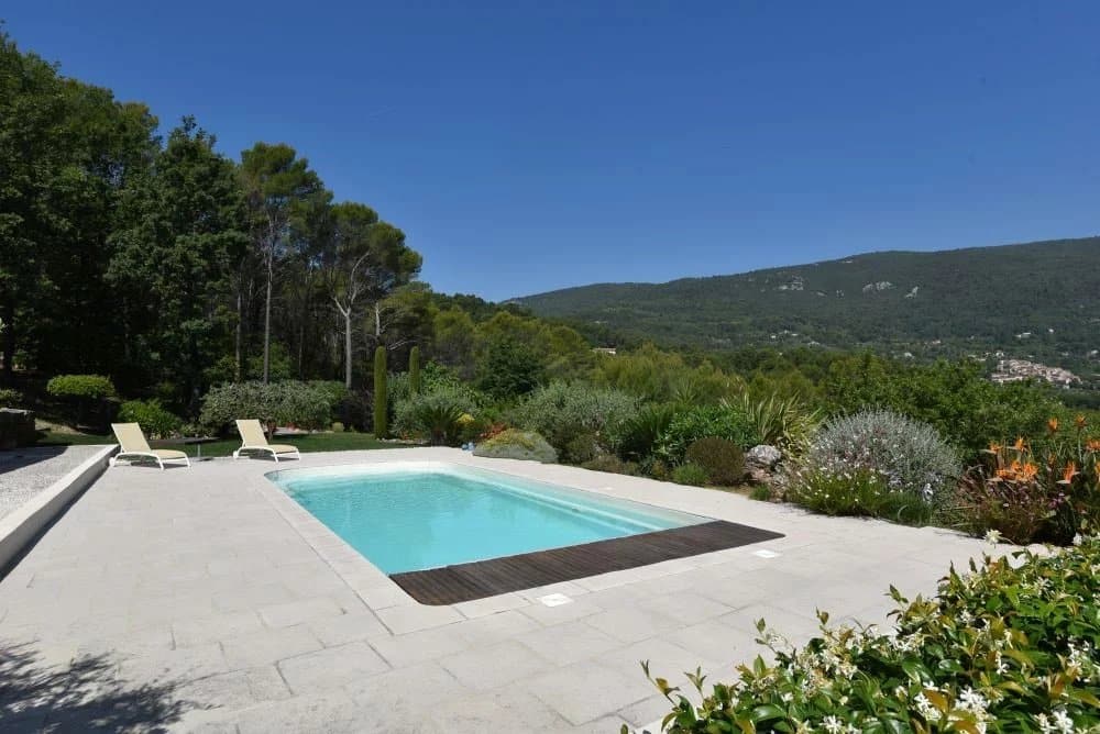Vue de la piscine d'une villa avec un paysage verdoyant et des collines en arrière-plan.