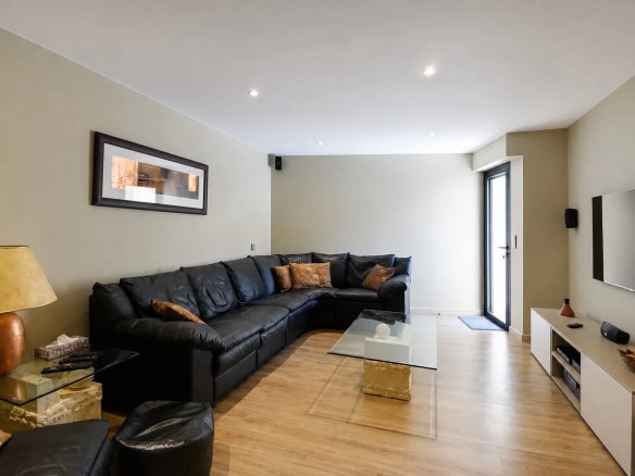 Intérieur d'un salon moderne avec canapé en cuir noir et table en verre.