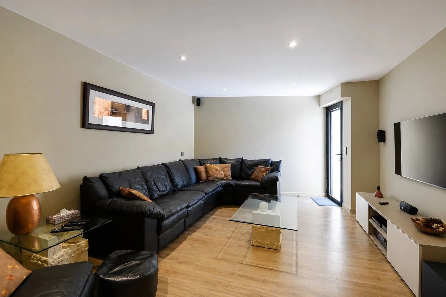 Intérieur d'un salon moderne avec canapé en cuir noir et table en verre.