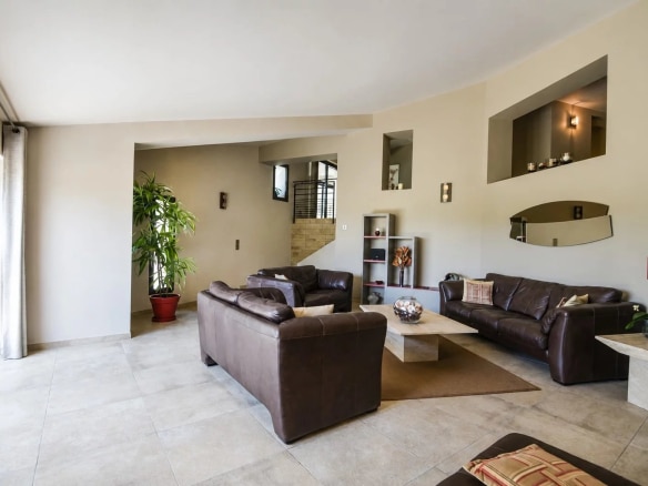 Intérieur d'une villa moderne avec salon spacieux et mobilier en cuir, éclairage naturel.