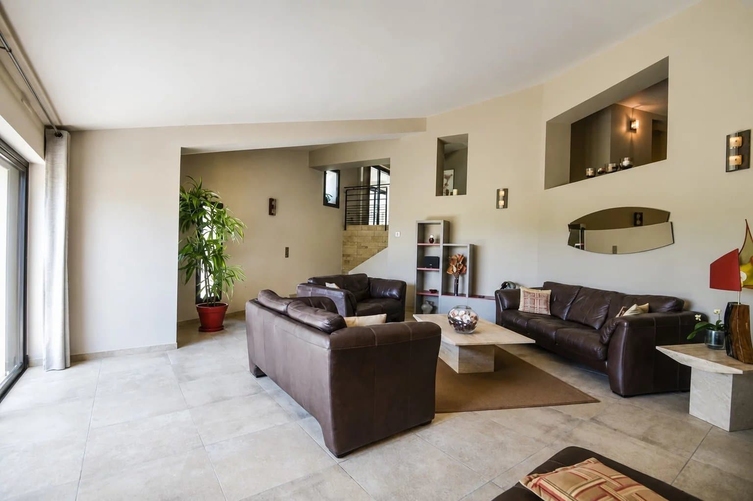 Intérieur d'une villa moderne avec salon spacieux et mobilier en cuir, éclairage naturel.