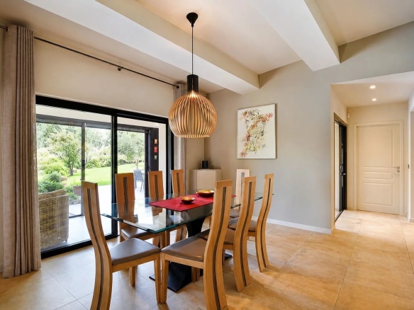 Salle à manger moderne avec table en verre et chaises en bois, vue sur le jardin.