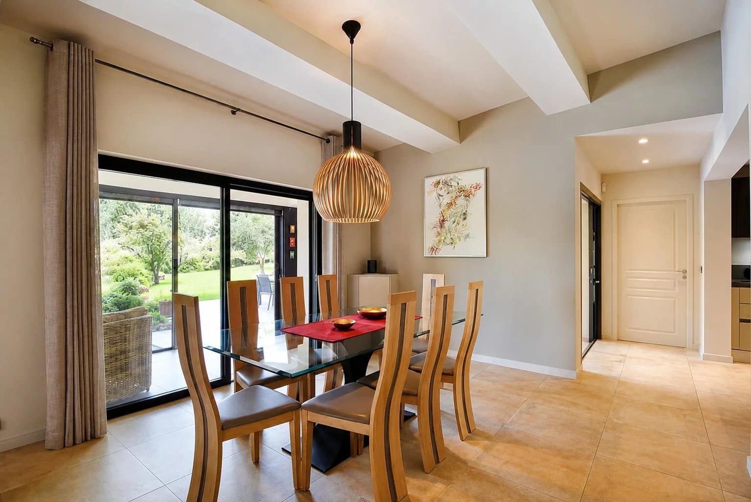 Salle à manger moderne avec table en verre et chaises en bois, vue sur le jardin.