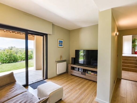 Intérieur d'une villa avec salon lumineux et accès à l'extérieur.