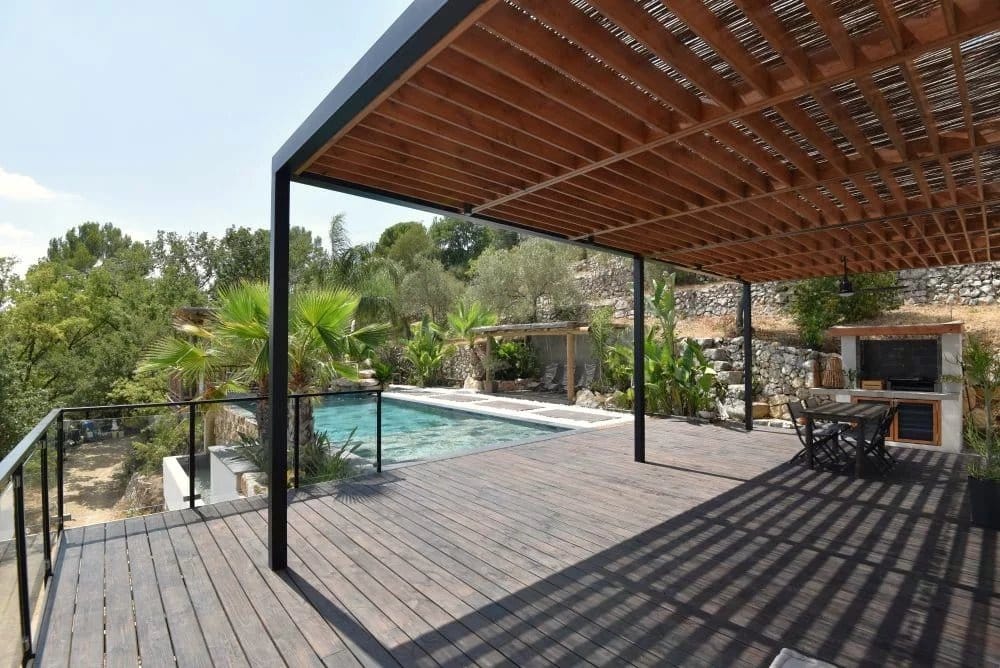 Terrasse en bois avec piscine et vue sur un jardin paysager à Fayence.