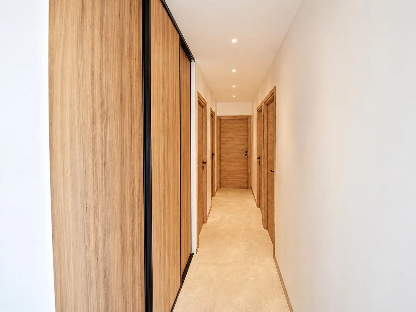Intérieur d'une villa contemporaine avec couloir et portes en bois clair.