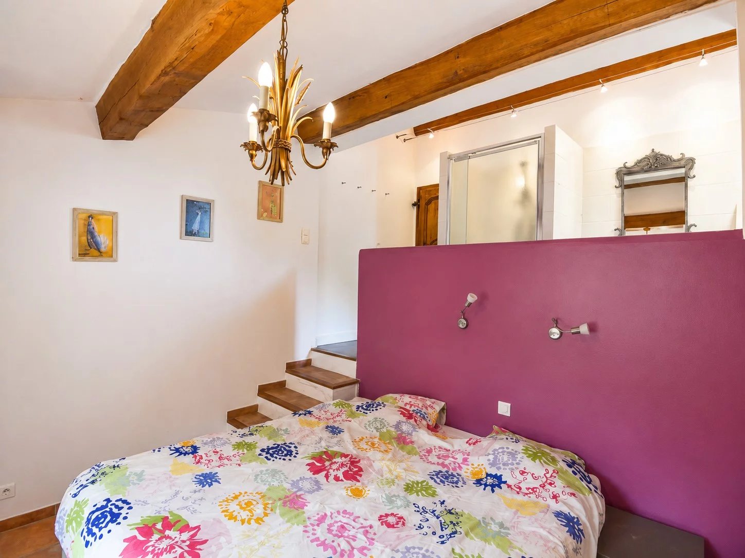 Chambre d'une maison en pierre avec lit et salle de bain attenante.
