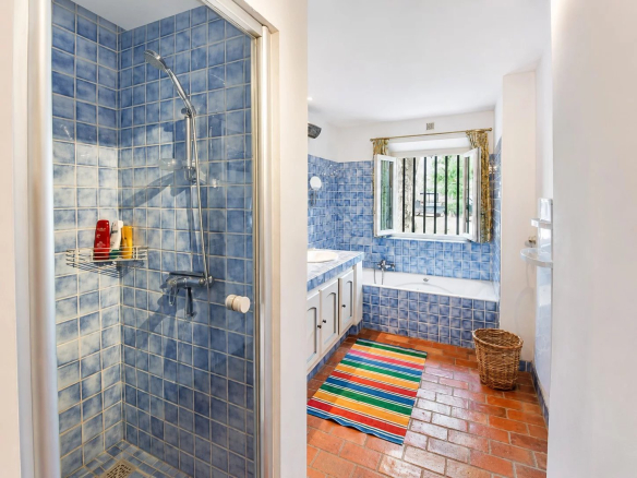 Salle de bain avec carrelage bleu, baignoire et douche dans une maison en pierre à Fayence.