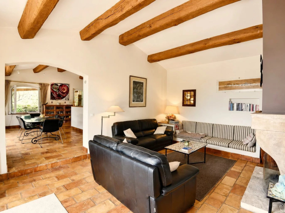 Intérieur d'une maison en pierre avec salon et cheminée, poutres apparentes