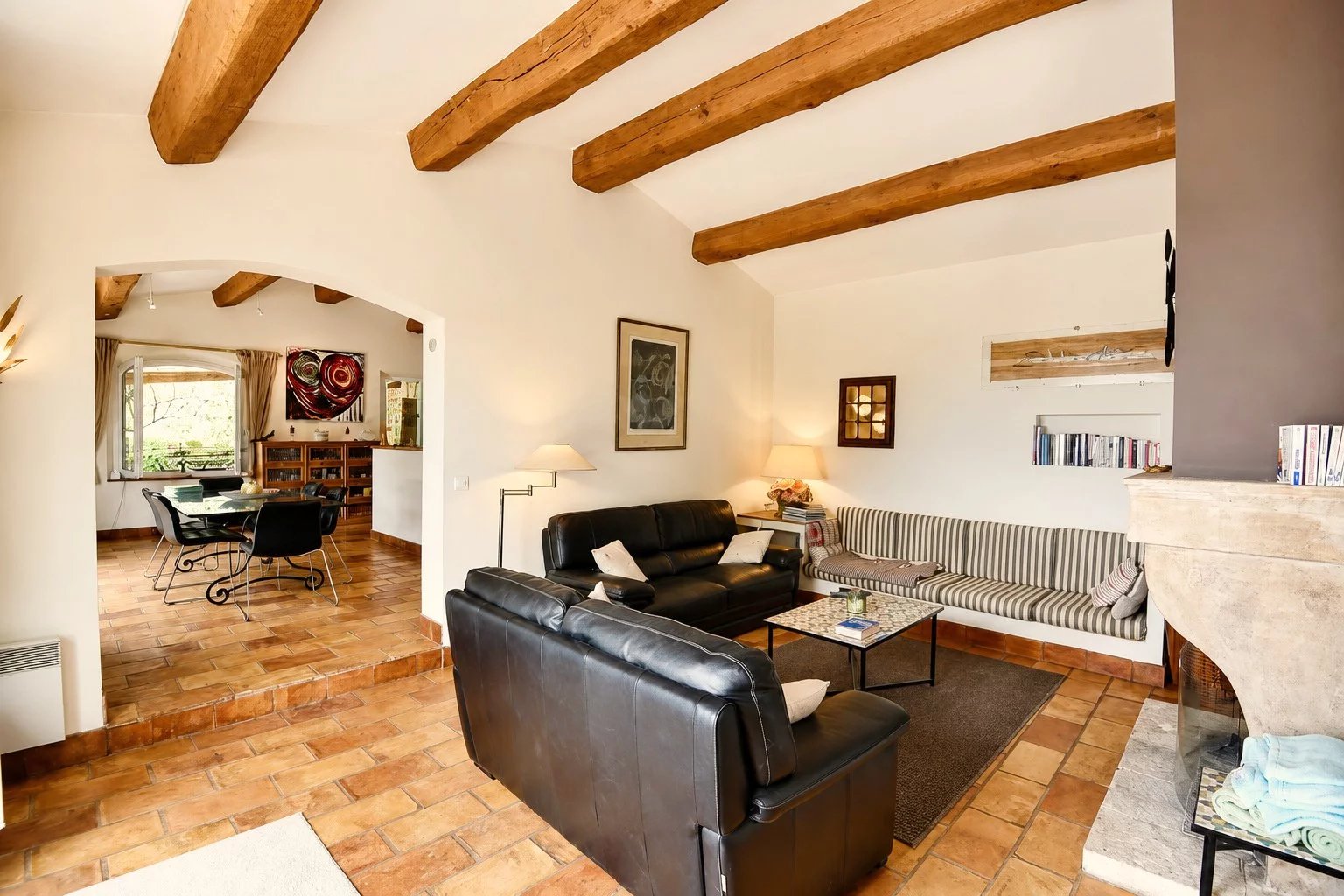 Intérieur d'une maison en pierre avec salon et cheminée, poutres apparentes