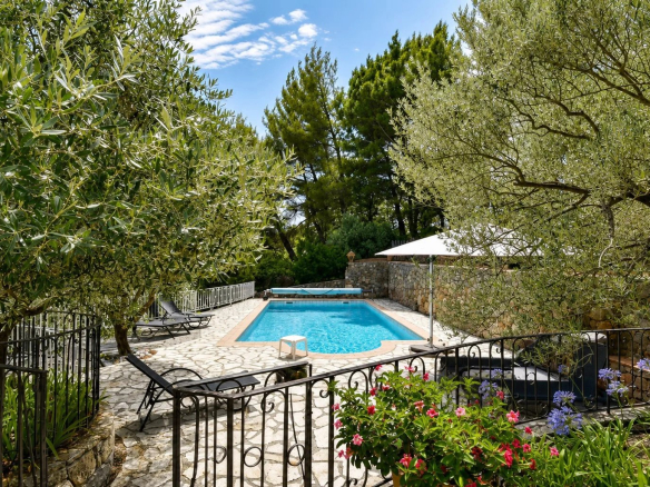 Piscine chauffée entourée d'oliviers et de fleurs dans une maison en pierre à Fayence.