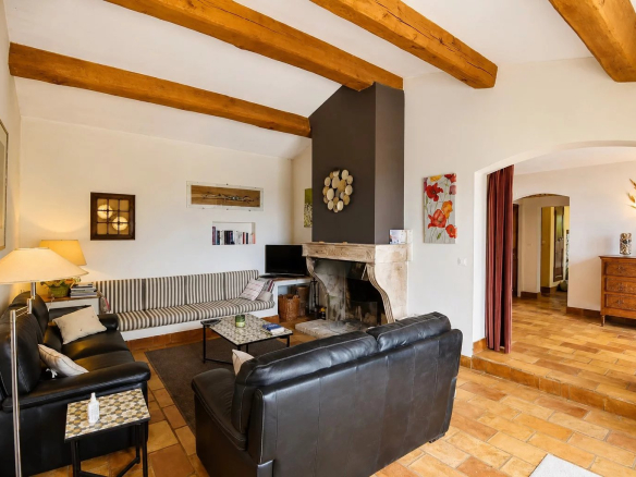 Intérieur d'une maison en pierre avec salon, canapés en cuir et cheminée.