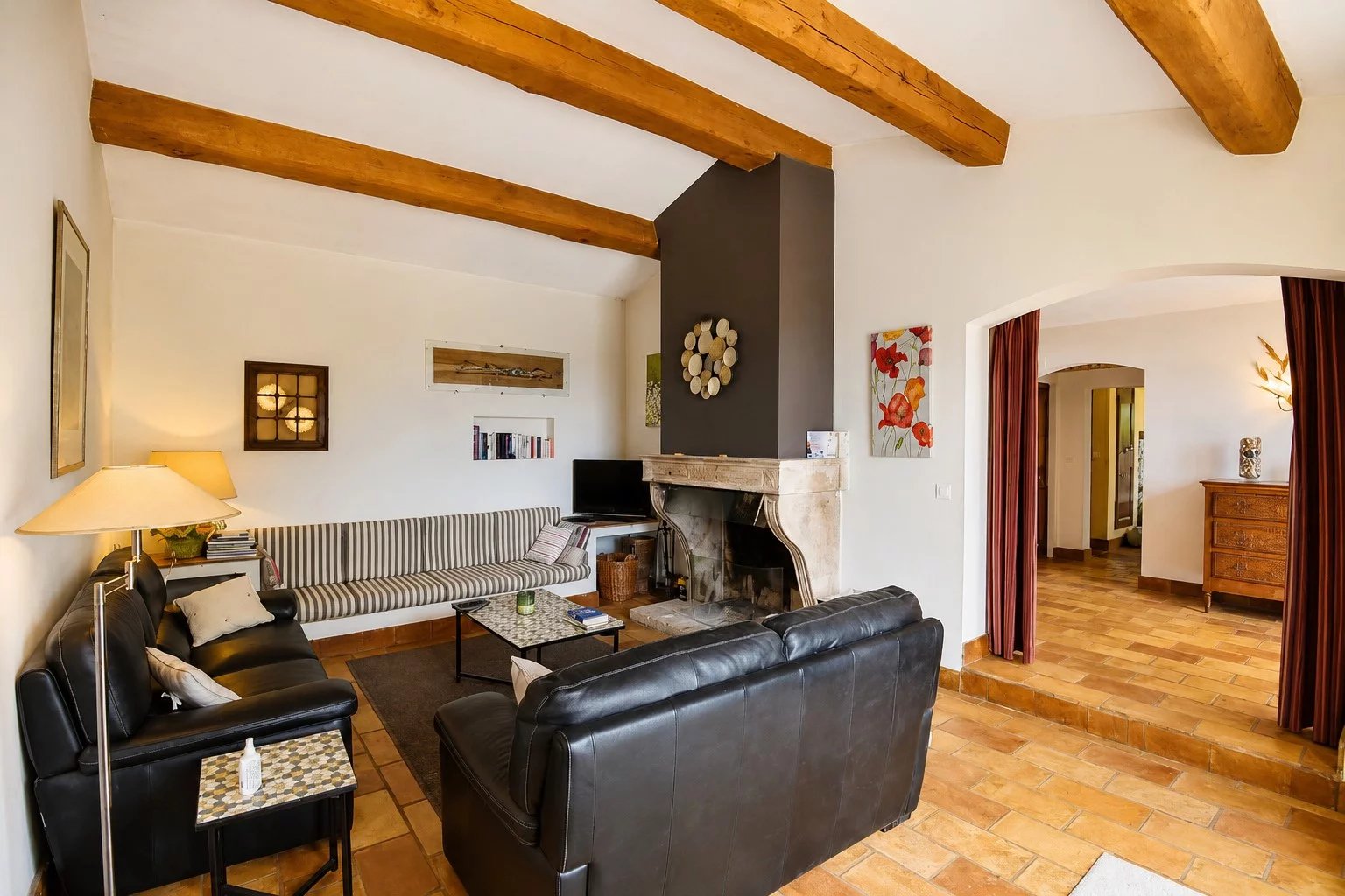 Intérieur d'une maison en pierre avec salon, canapés en cuir et cheminée.