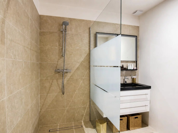 Salle de bain moderne avec douche en verre et meuble sous vasque.