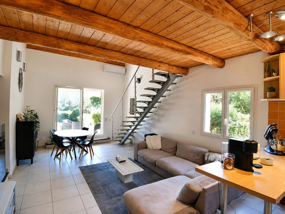 Intérieur d'une villa à Bagnols-en-Forêt avec salon, cuisine ouverte et escalier en colimaçon.