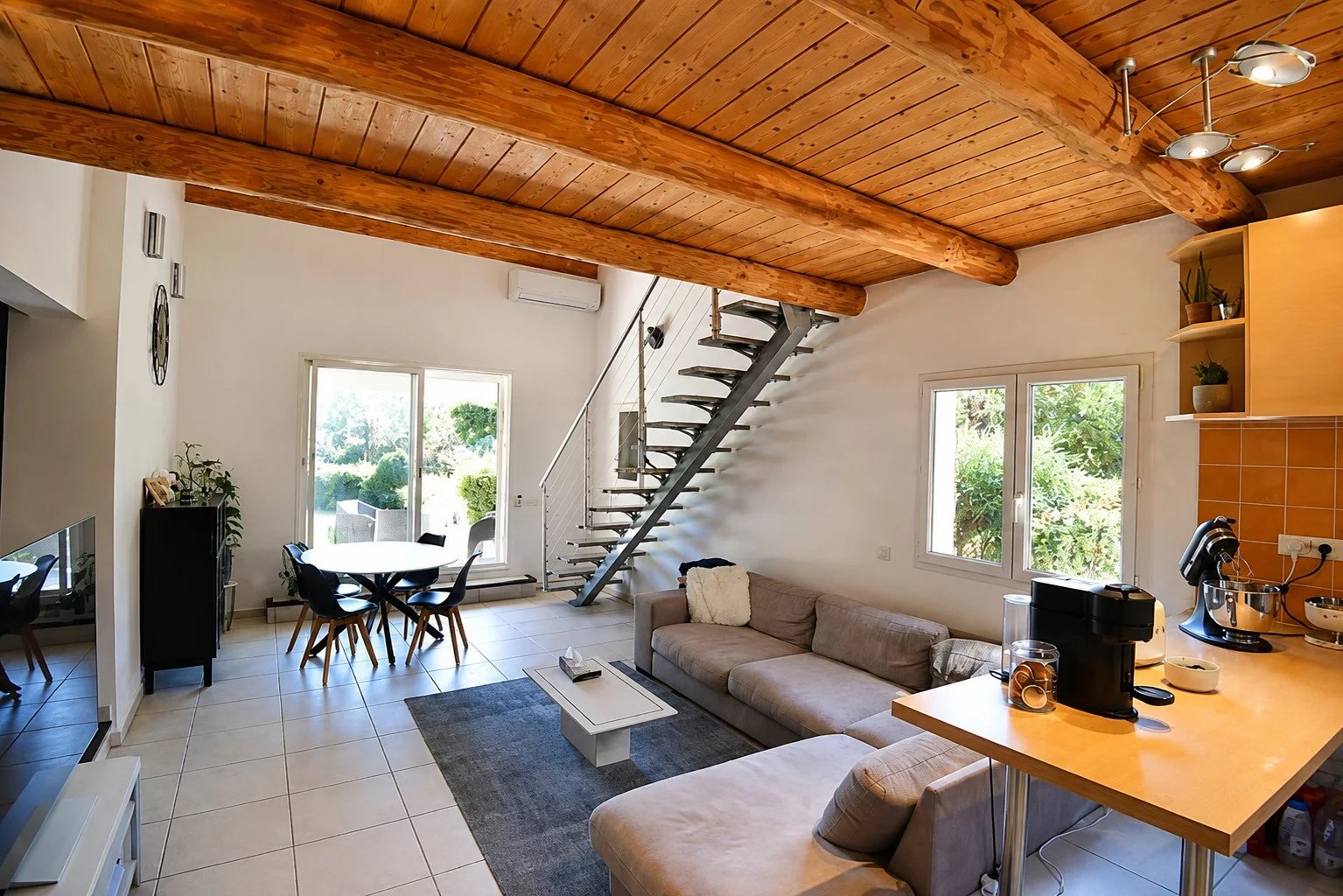 Intérieur d'une villa à Bagnols-en-Forêt avec salon, cuisine ouverte et escalier en colimaçon.