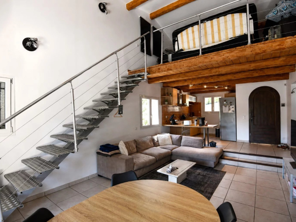 Intérieur d'une villa moderne avec mezzanine, salon et coin repas, décoré dans un style contemporain.