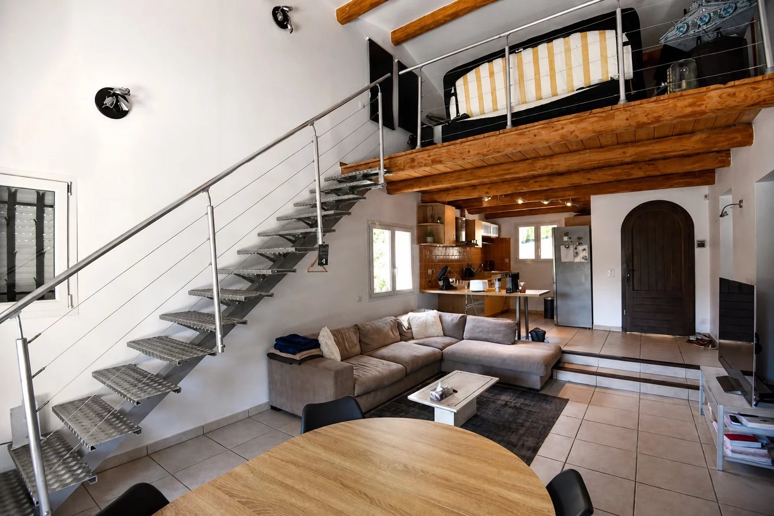 Intérieur d'une villa moderne avec mezzanine, salon et coin repas, décoré dans un style contemporain.