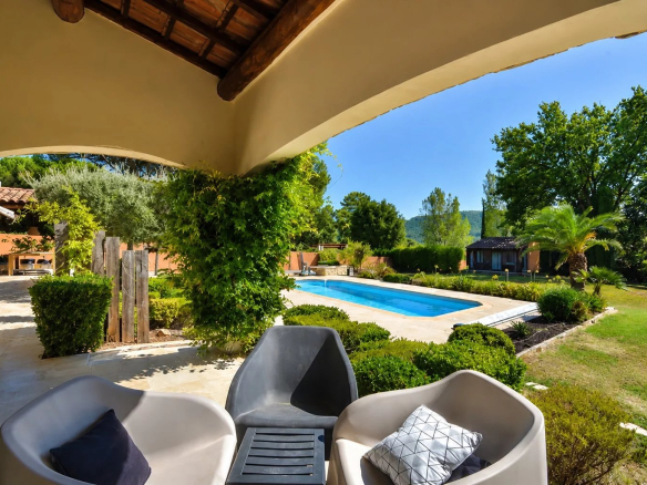 Vue d'une villa avec piscine et jardin à Bagnols-en-Forêt, entourée de verdure.