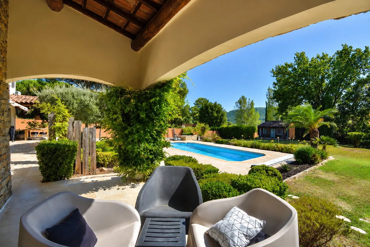 Vue d'une villa avec piscine et jardin à Bagnols-en-Forêt, entourée de verdure.