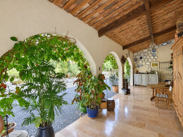 Intérieur d'une villa à Tourrettes avec arches et plantes, décoré de vaisselle sur un mur.