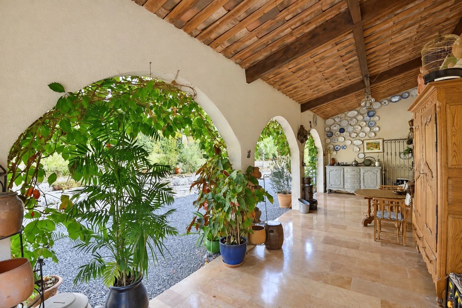 Intérieur d'une villa à Tourrettes avec arches et plantes, décoré de vaisselle sur un mur.