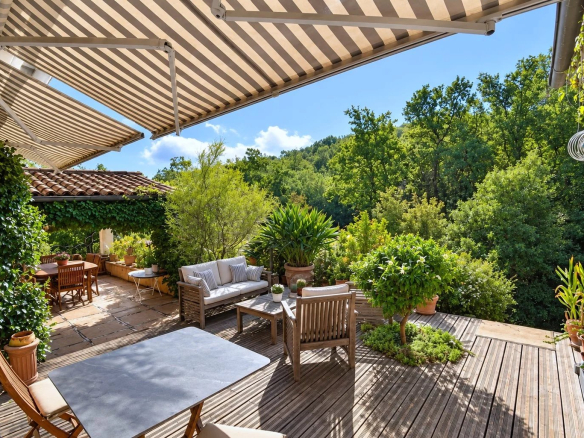 Terrasse en bois avec mobilier de jardin entourée de verdure.