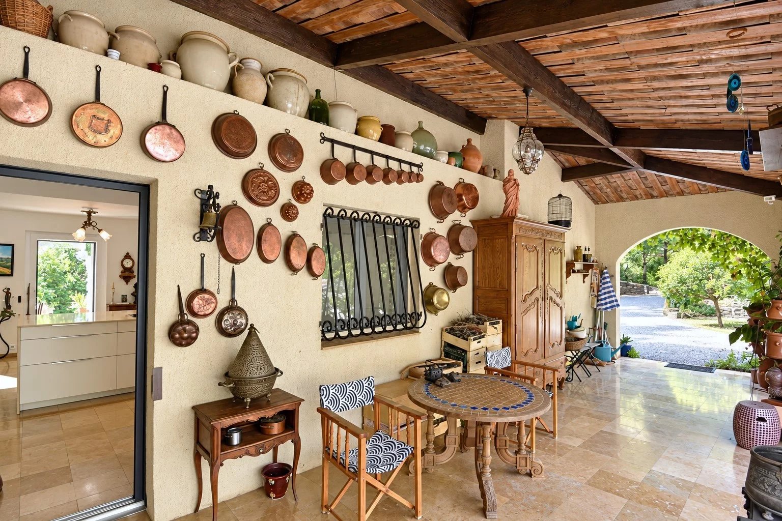 Terrasse couverte d'une villa avec décoration en cuivre et mobilier en bois à Tourrettes.