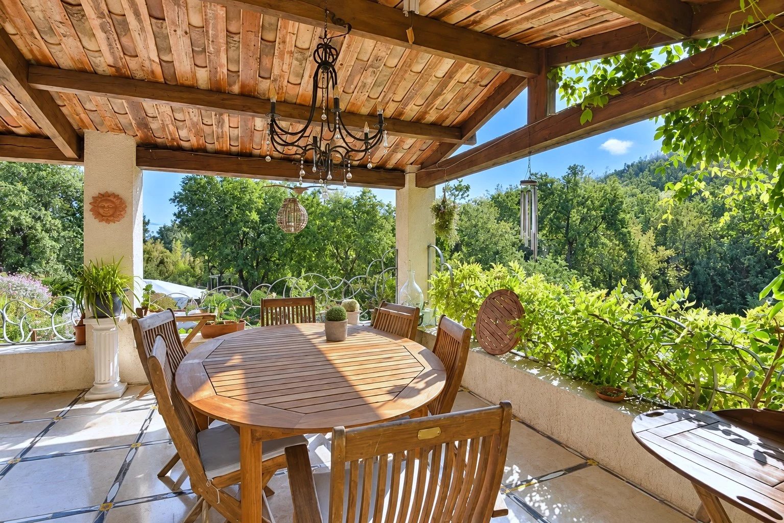 Terrasse en bois avec table et chaises, entourée de verdure, à Tourrettes.