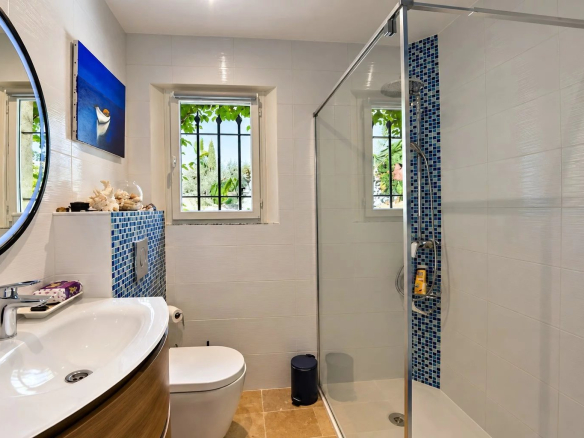 Salle de bain moderne avec douche, lavabo et toilettes, décorée de carrelage blanc et bleu.