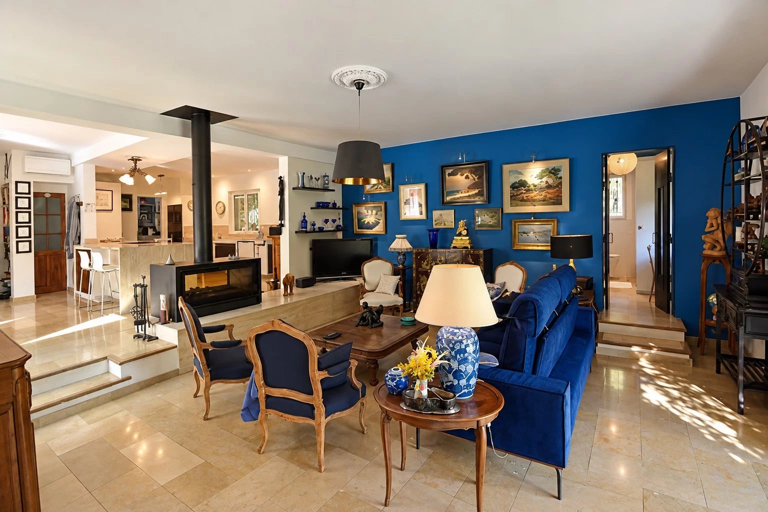 Intérieur d'une villa spacieuse avec salon, cheminée et décor artistique.