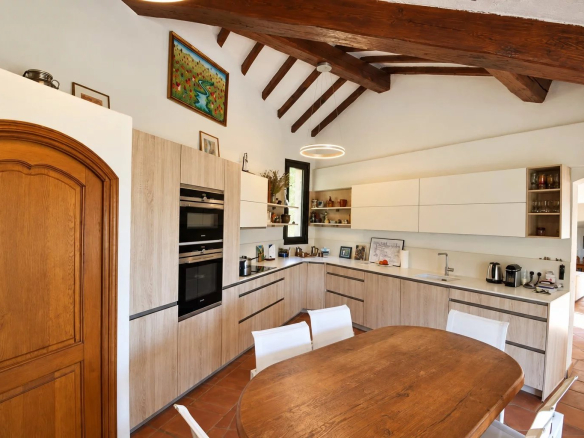 Modern kitchen with wooden table and beamed ceiling in a property in Callian.