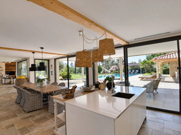 Interior of a contemporary villa with open kitchen and dining room, overlooking the outdoor pool.