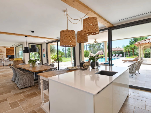 Interior of a contemporary villa with open kitchen and view of the outdoor pool in Tourrettes.