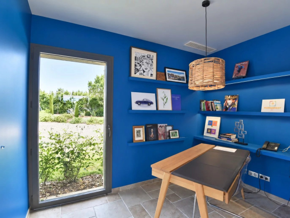 Modern office with blue walls and a view of a landscaped garden.
