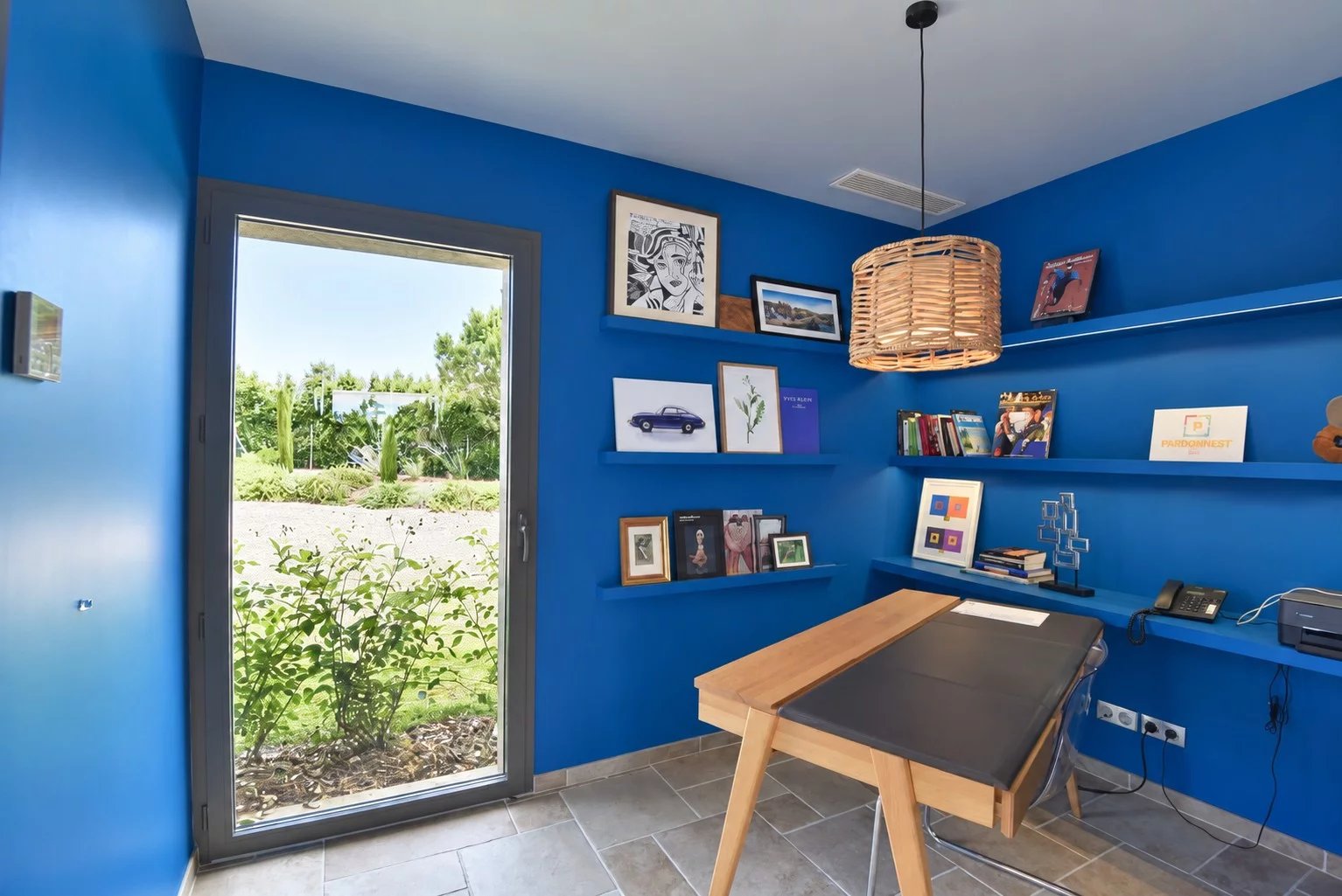 Contemporary office in a luxury villa Modern office with blue walls and a view of a landscaped garden.