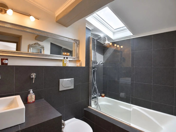Salle de bain moderne avec baignoire et douche, murs carrelés en noir et blanc.